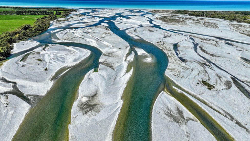 Aerial view of a branching river flowing around pale sandbars